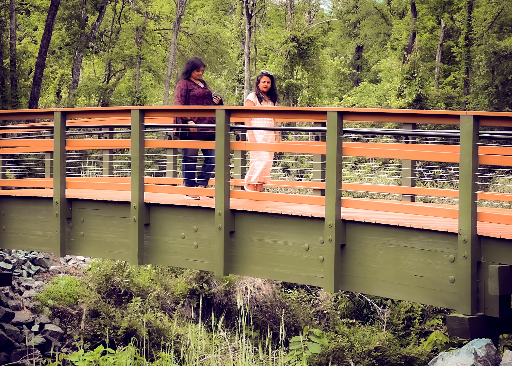 Walkers crossing a bridge enjoying the Back Creek Greenway